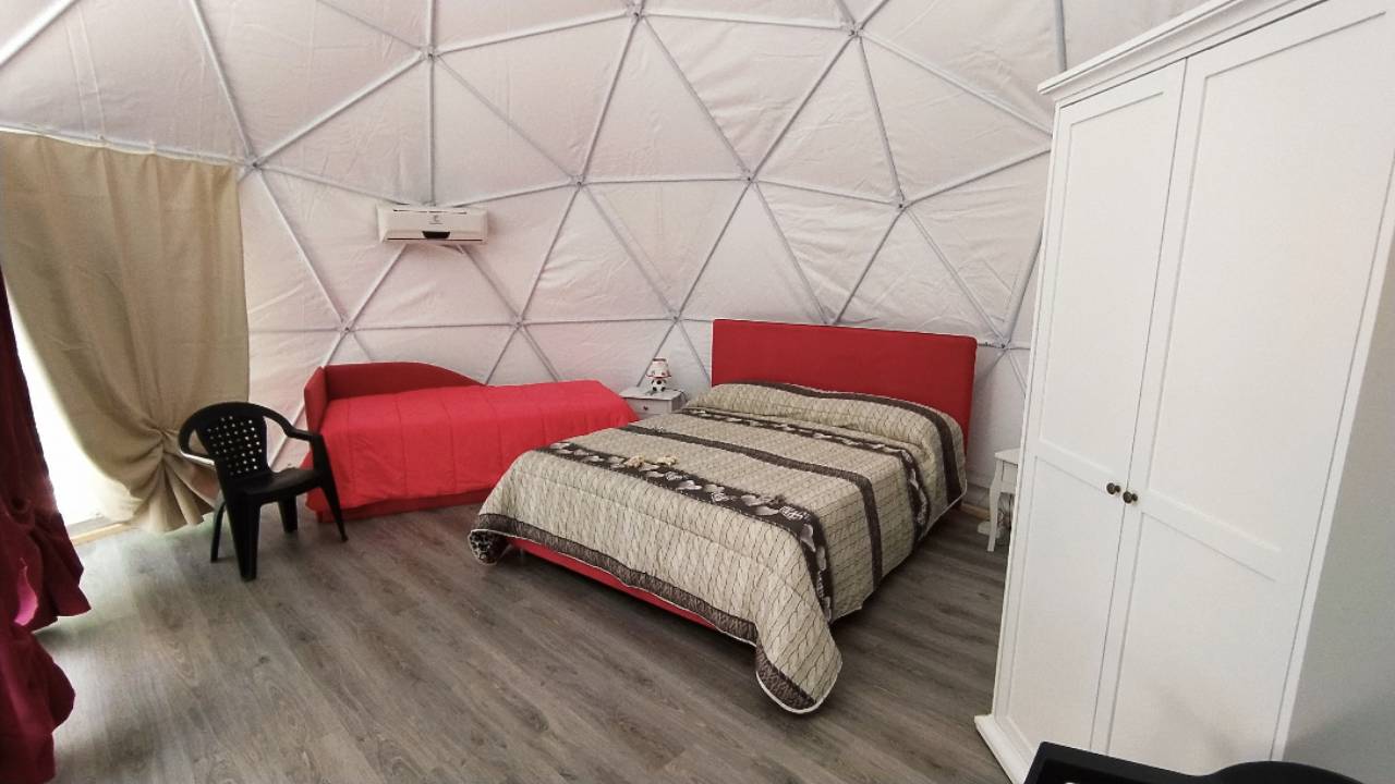 Interno di una cupola glamping con letto matrimoniale