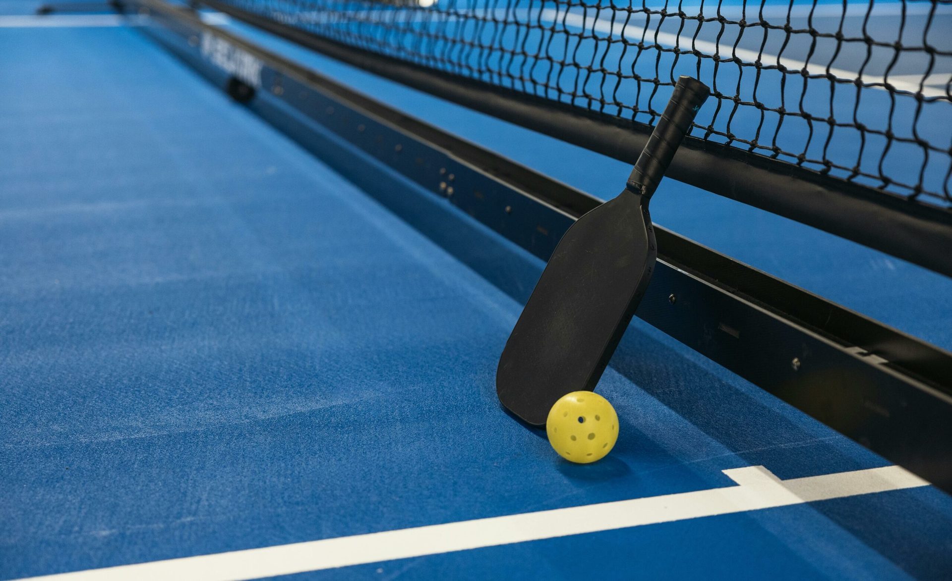 Racchetta e pallina da pickleball sul campo blu