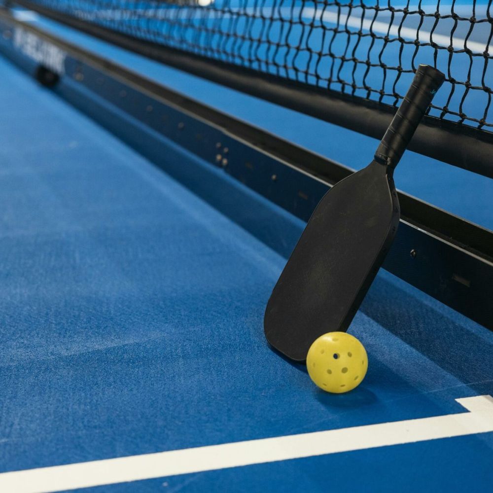 Racchetta e pallina da pickleball sul campo blu